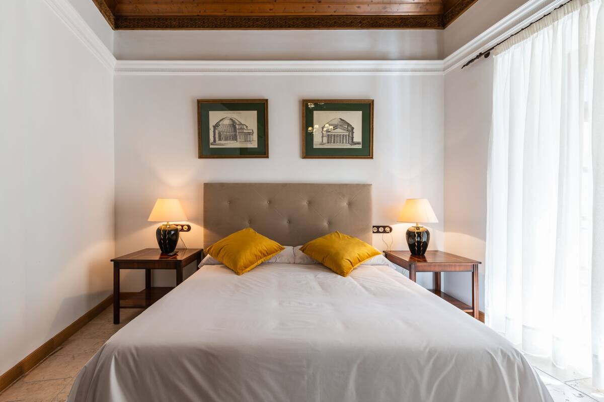 A hotel room with a large bed, two bedside tables with lamps, and two framed pictures on the wall.