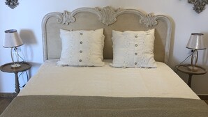 Una cama con cabecera, dos almohadas, un edredón con textura y dos mesitas de noche con lámparas.