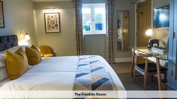 A hotel room with a large bed, a desk, and a window.