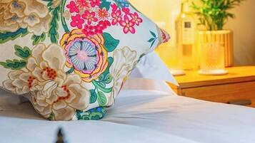 A bed with a floral pillow, a bedside table with a lamp, and a decorative item.