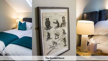 A hotel room with two beds, teal bedding, a framed picture of animals, and a bedside lamp.