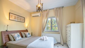 Un dormitorio con cama, mesita de noche, cómoda y ventana con cortinas.