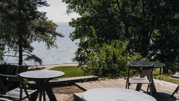 Un espace extérieur aménagé avec des tables et des chaises, offrant une vue sur la plage.