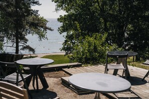 An outdoor seating area with tables and chairs overlooking a beach. - Kastytis (Neringa)