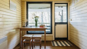 Une pièce d’angle avec une table en bois, deux chaises, une fenêtre donnant sur un beau paysage et un radiateur.