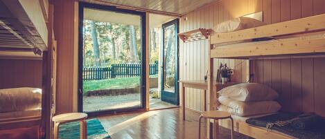 A wooden cabin with bunk beds, a small table, and a bench.