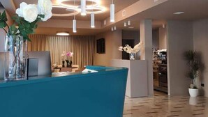 A reception area with a blue counter, modern pendant lighting, and a polished wooden floor.