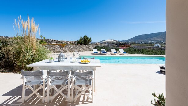 Un área junto a la piscina con mesa y sillas, una piscina y vistas del paisaje.