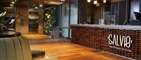 A modern reception area with a wooden ceiling, a reception desk, and a seating area with a green sofa.