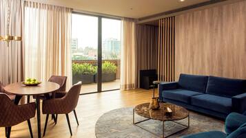 A modern living room with a blue sofa, a round coffee table, and a dining area with a wooden table and chairs.