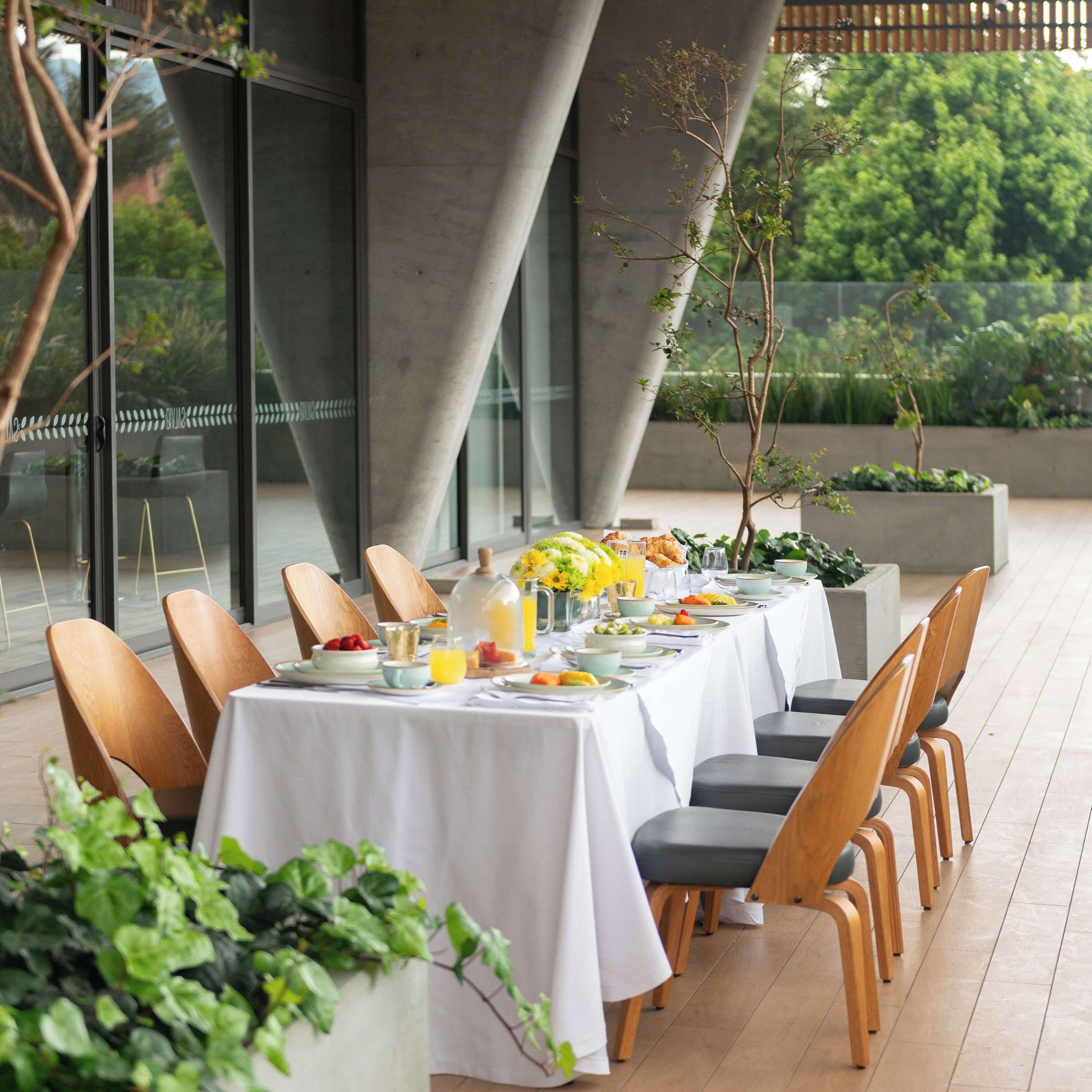 A dining area with tables set for breakfast, featuring a variety of dishes and drinks.
