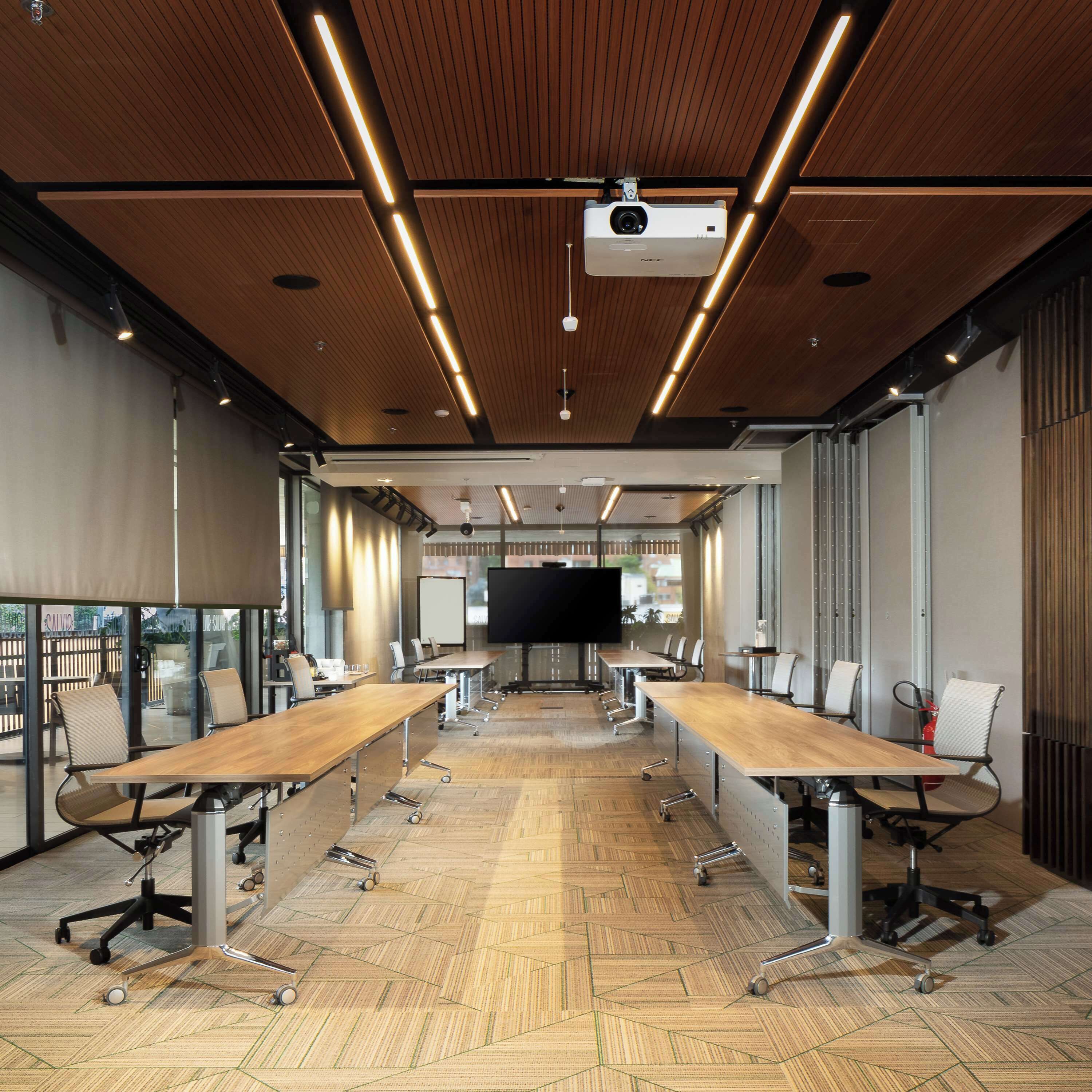 A conference room with a long table, chairs, a projector, and a large screen.