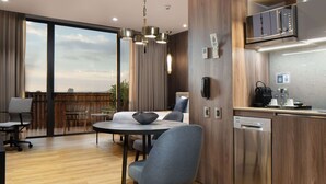 A modern kitchen with a built-in oven, a coffee machine, and a dishwasher. There is a dining area with a round table and chairs.