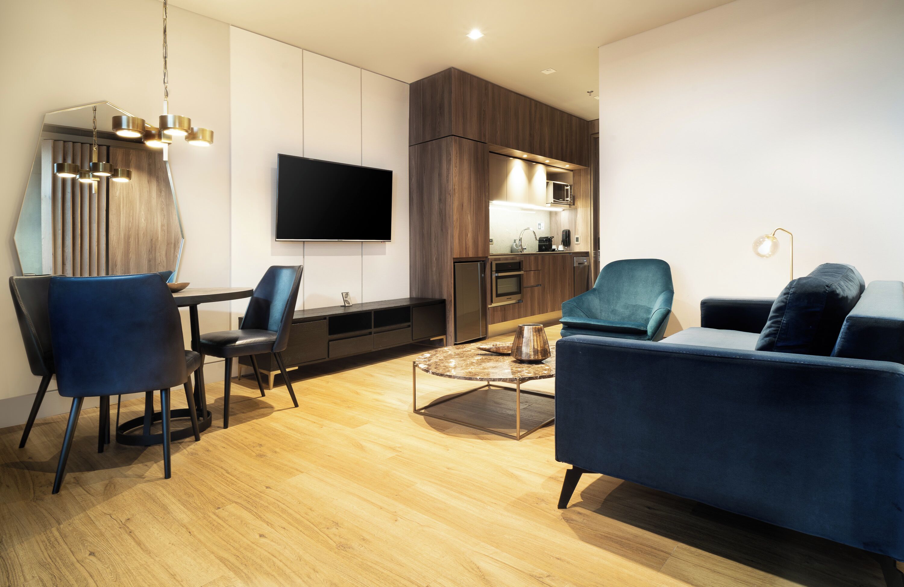 A modern living room with a sofa, chairs, a coffee table, and a TV.