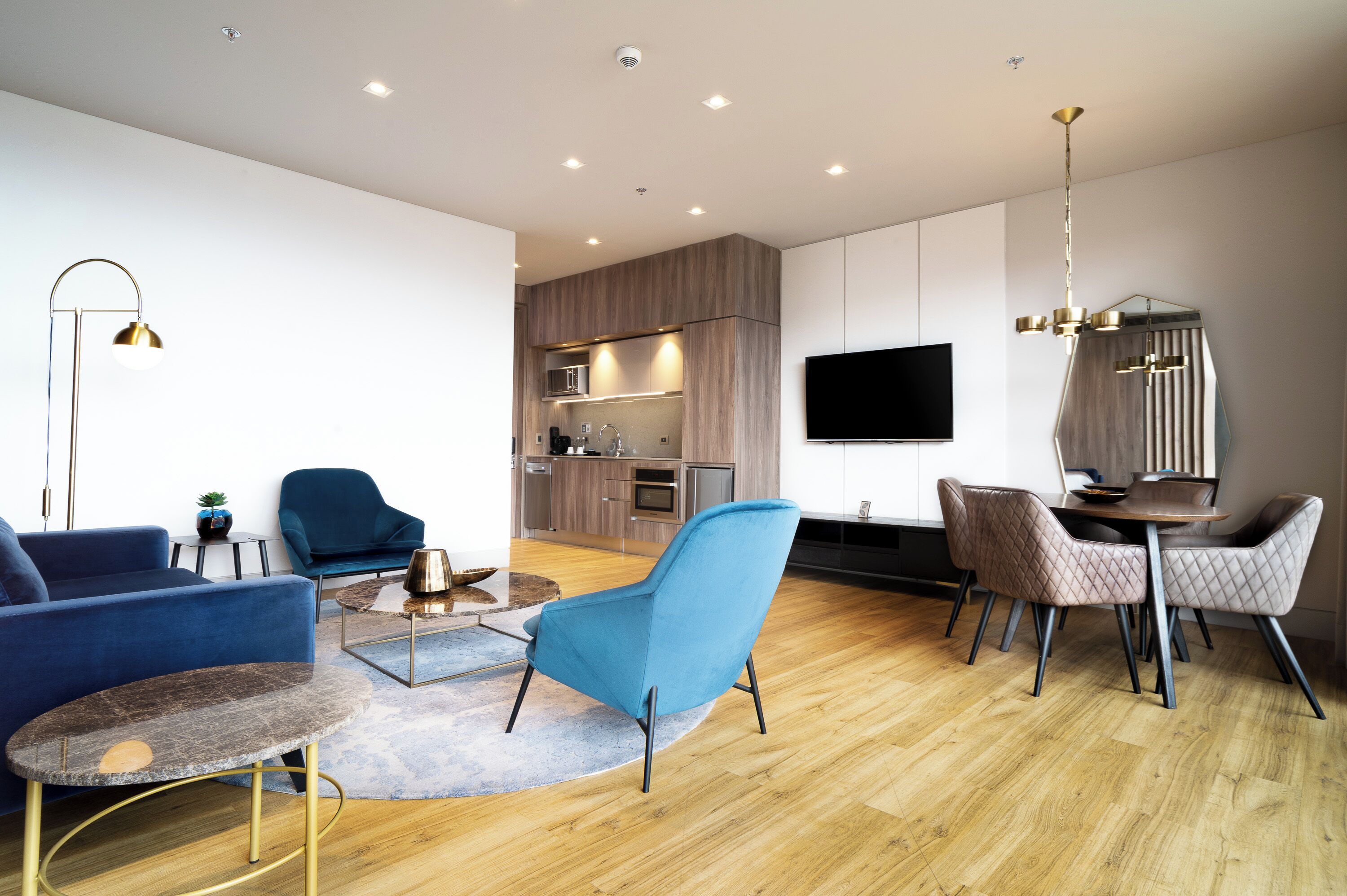 Una sala de estar moderna con sofá, sillón, mesa de centro y comedor.
