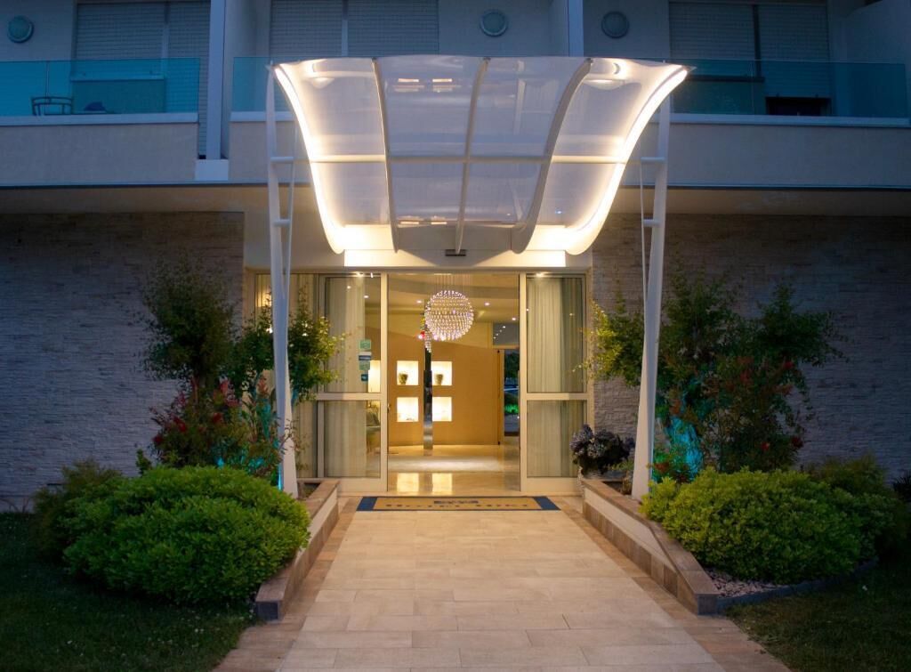 A hotel entrance with a glass door, a covered walkway, and a decorative light fixture.