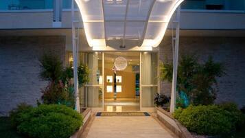 A hotel entrance with a glass door, a covered walkway, and a decorative light fixture.