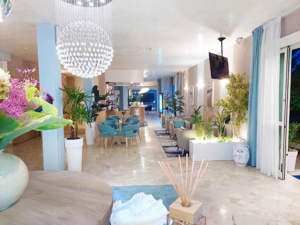 A spacious lobby with a chandelier, seating area, and potted plants.