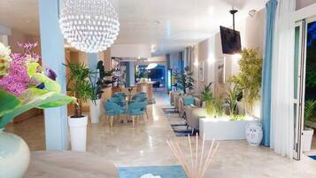 A spacious lobby with a chandelier, seating area, and potted plants.