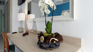 Eine Küchenarbeitsplatte mit einer weißen Orchidee, einer Lampe und einem Spiegel darüber.