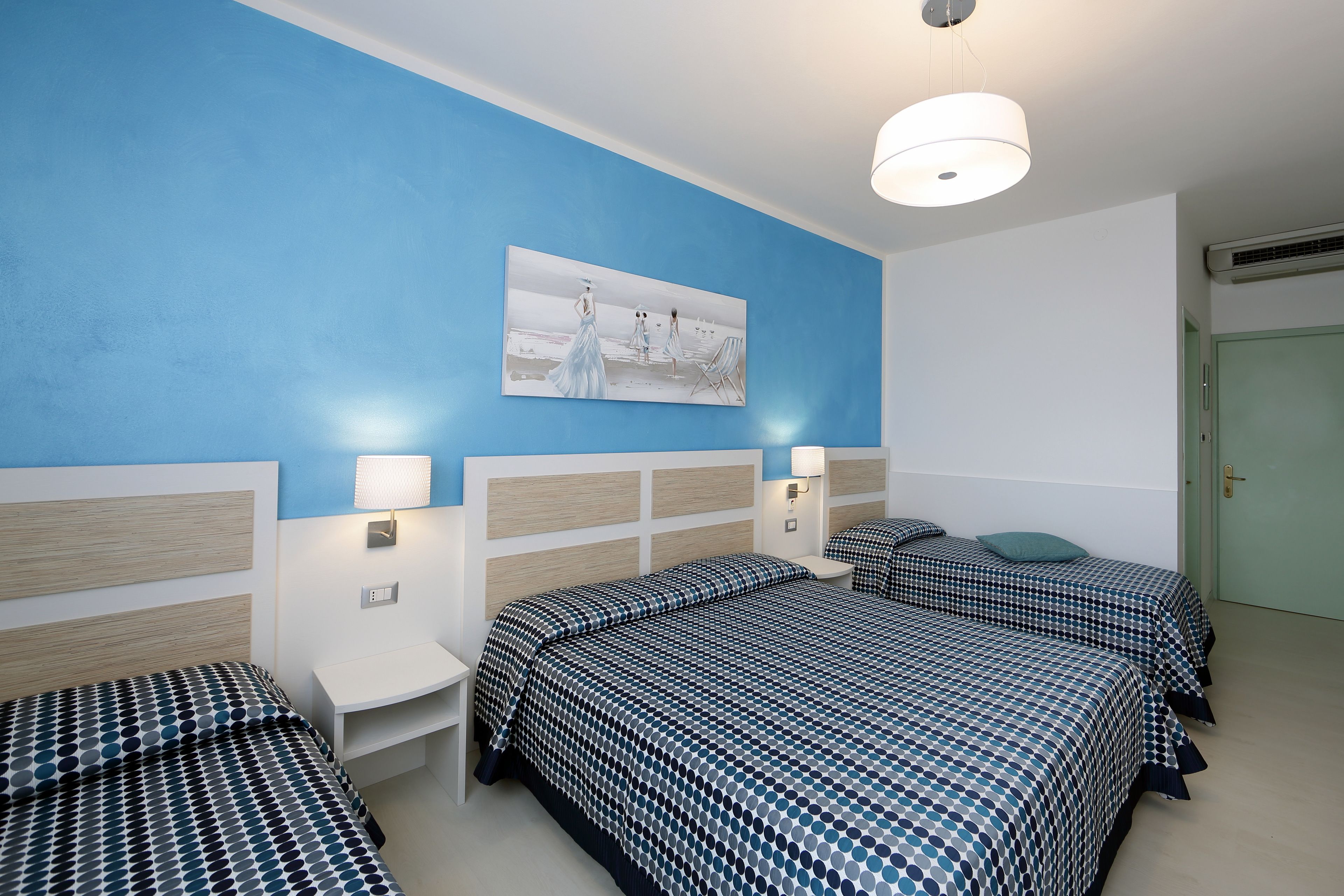 Une chambre d’hôtel avec deux lits, une table de chevet, une lampe et un tableau au mur.