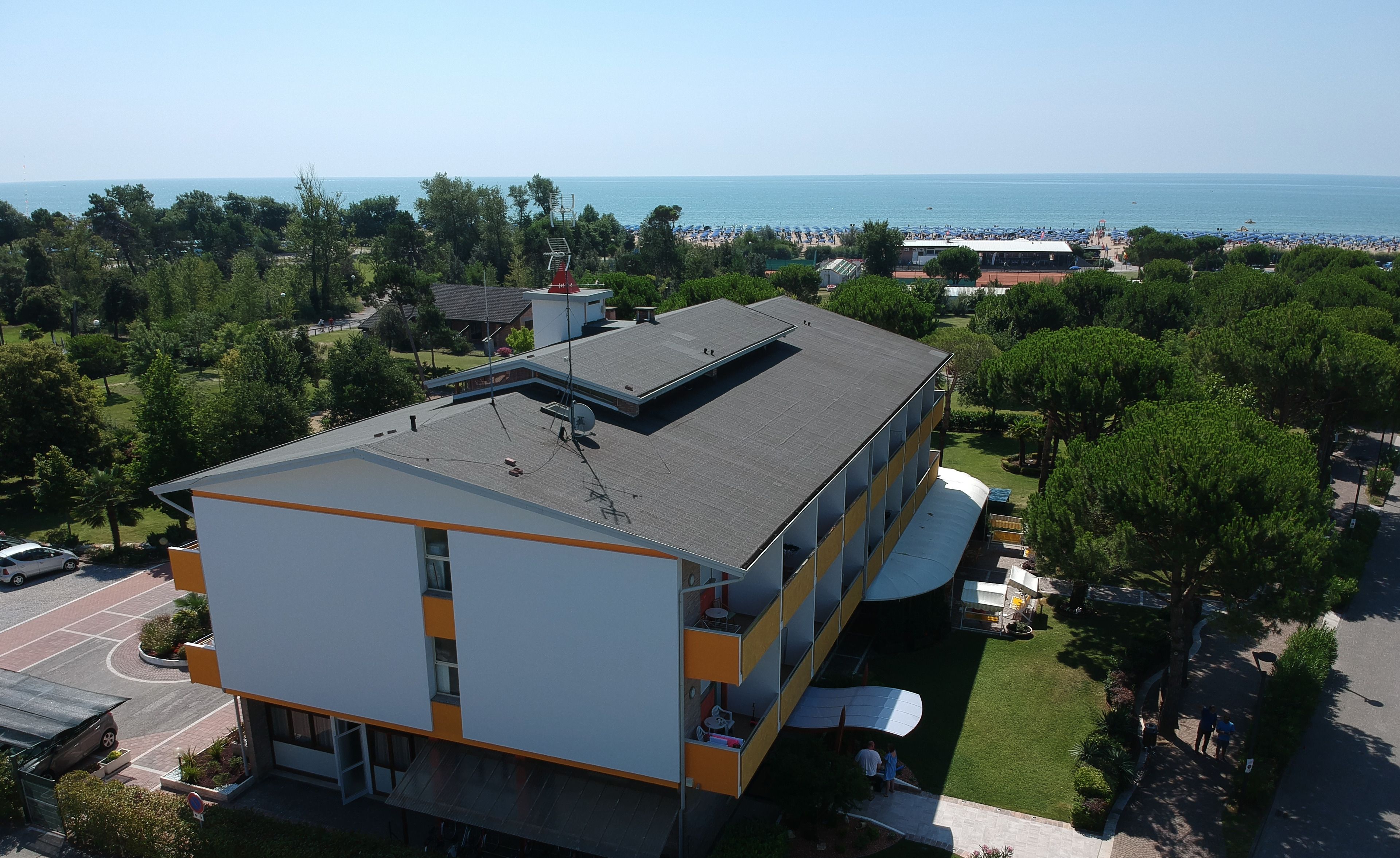 A modern building with a flat roof, multiple balconies, and a view of the sea.
