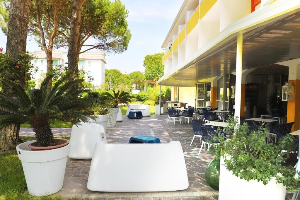 An outdoor patio area with seating, potted plants, and a building in the background.