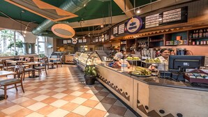 A cafe with a checkered floor, a counter with a display case, and a menu board.