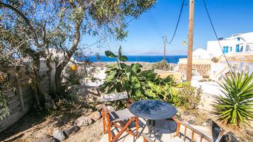 A patio with a table and chairs, overlooking a coastal landscape with buildings and the sea.