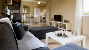 Een moderne woonkamer met een bank, een salontafel en een televisie op een wit dressoir.