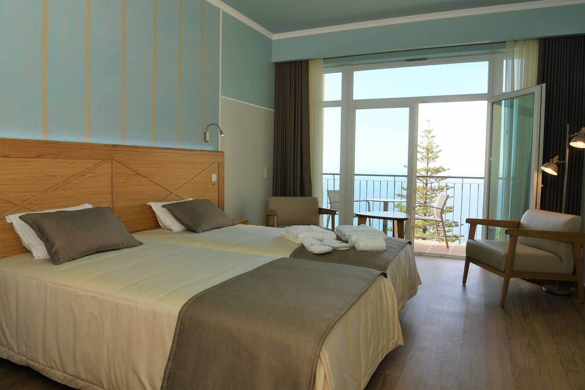 A hotel room with two beds, a balcony, and a seating area.