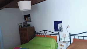 Quarto com duas camas, teto de madeira, mesa de cabeceira, luminária e um quadro na parede.