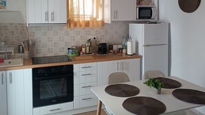Uma cozinha moderna com armários brancos, teto de madeira, luminária pendente, micro-ondas e geladeira.