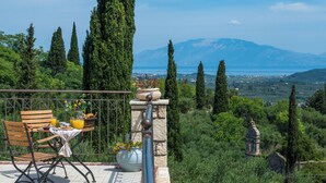 Una terrazza con un tavolo apparecchiato per la colazione, affacciata su un paesaggio montuoso.
