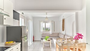 Una cocina moderna con horno empotrado y zona de comedor con mesa y sillas de madera.