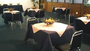 Une salle de conférence équipée de plusieurs tables, de chaises et de plantes en pot.