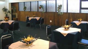 Une salle de conférence équipée de plusieurs tables, de chaises et de plantes en pot.