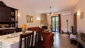 A dining area with a table set for two, a fireplace, and a sofa. - Modern Countryside Villa with Private pool, spectacular view, peaceful location (Πρινές)