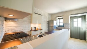 Een moderne keuken met een spatwand van natuursteen, een inbouwfornuis en een groot raam.