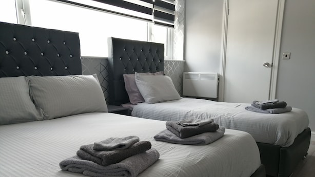 A hotel room with two beds, each with a headboard, and a set of towels on the beds. - Encore Rooms (Scunthorpe)