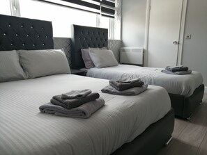 Une chambre d’hôtel avec deux lits, chacun doté d’une tête de lit, et un ensemble de serviettes posé sur les lits.