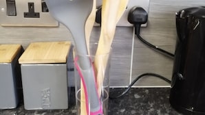 A kitchen counter with a clear plastic container holding a spatula and wooden utensils, a power outlet, and a coffee maker. - Encore Rooms (Scunthorpe)