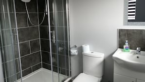 A bathroom with a glass-enclosed shower, a toilet, and a sink with a soap dispenser. - Encore Rooms (Scunthorpe)