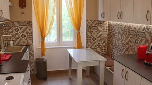 Eine kleine Küche mit Fenster, Musterfliesen und einem Tisch.