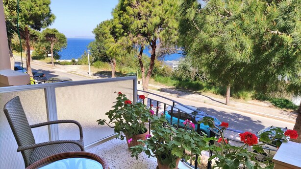 Ein Balkon mit Korbmöbeln, Blumentöpfen und Blick aufs Meer.