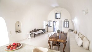 A spacious living area with a dining table, sofa, and a bowl of fruit on a counter. - Winery Villa. Old winery converted into a stylish traditional villa with pool (Φοινικιά)