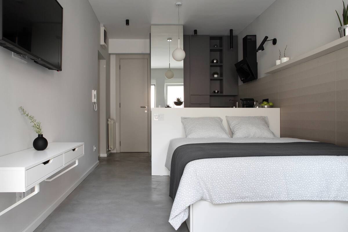 A modern bedroom with a bed, bedside console, and a TV mounted on the wall.