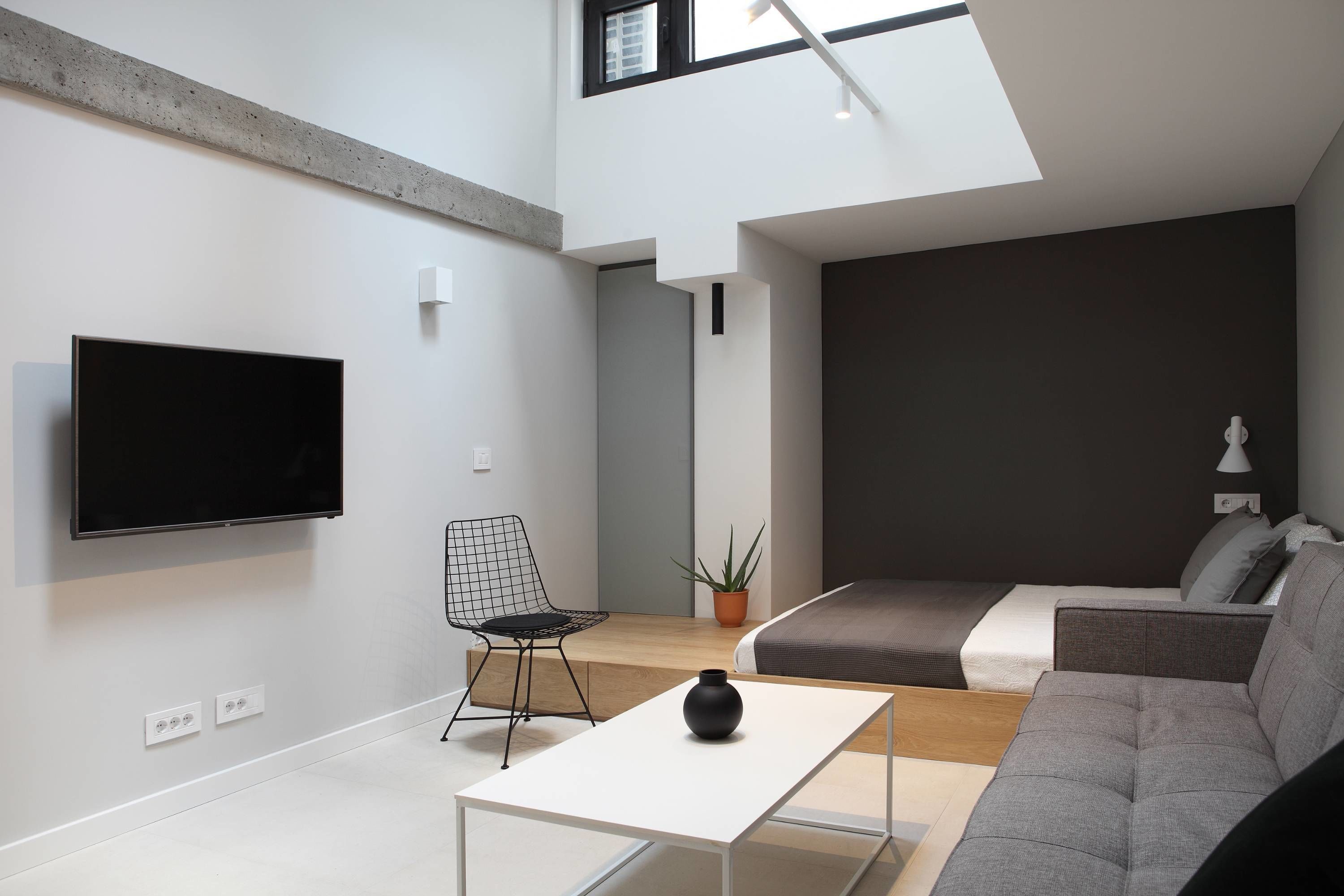 A modern living room with a flat-screen TV, a sofa, a coffee table, and a chair.
