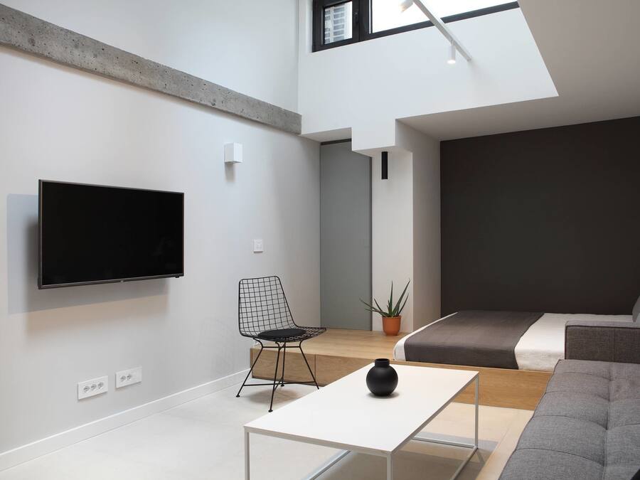 A modern living room with a flat-screen TV, a sofa, a coffee table, and a chair.