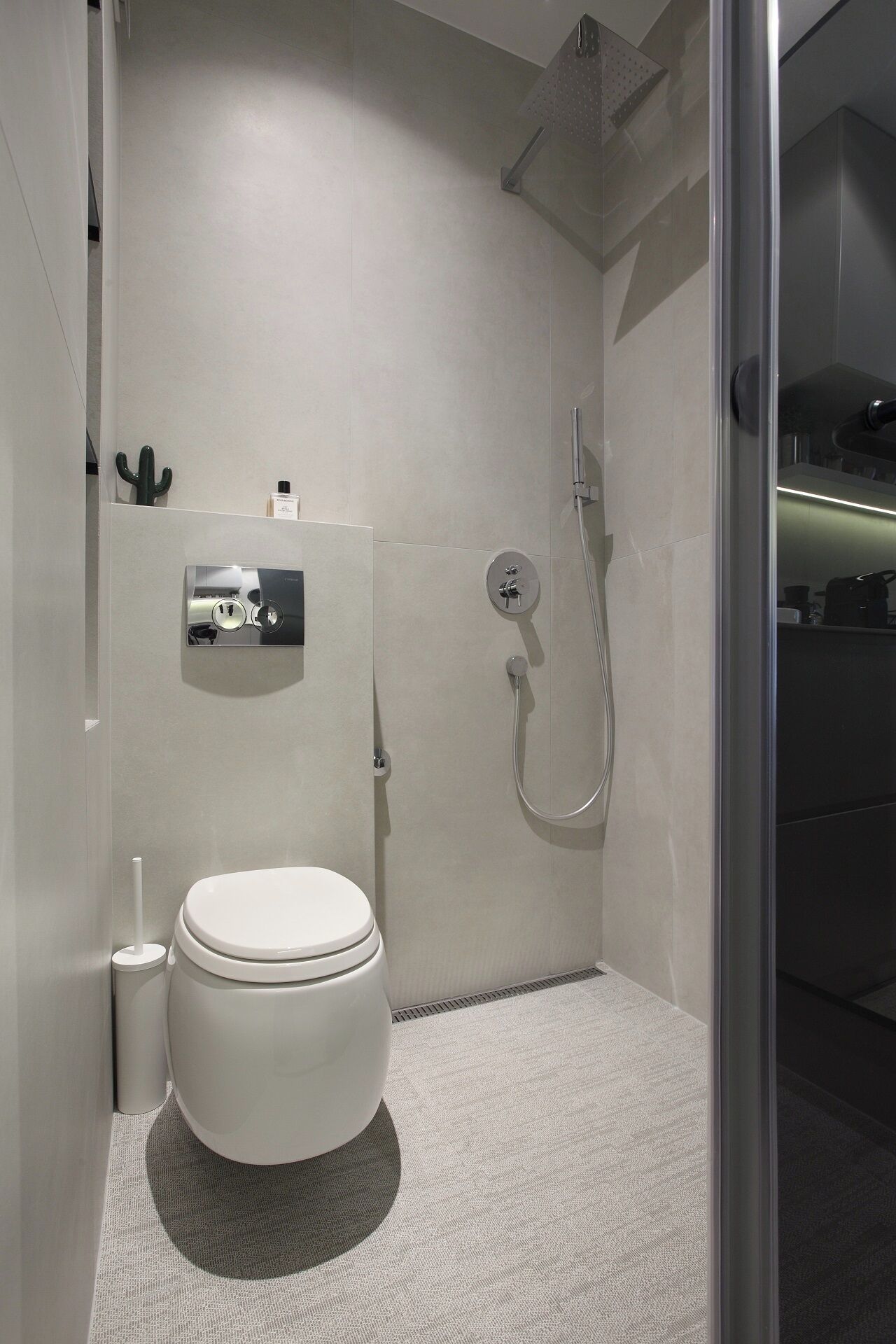 Un bagno moderno con un WC, una doccia e un piccolo ripiano con articoli da toilette.